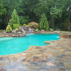 Freeform pool in a natural setting with Verde pool finish