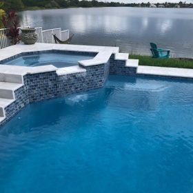photo of pool and spa on a lake with Diamond Brite Jewels Blue Topaz exposed aggregate finish. Installed by Pinch A Penny #112