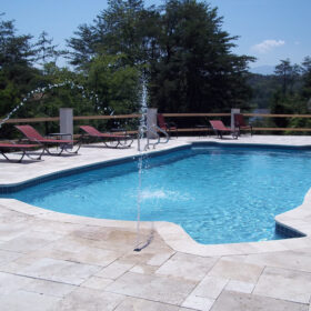 A pool with steps in all four corners on a sunny patio.