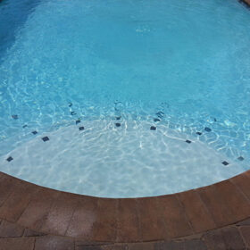 Up close photo of the steps of a pool finished in Diamond Brite Blue Quartz.