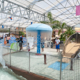 Indoor area of a splash park with various water features and tubes for floating.