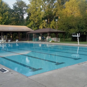 Outdoor competition pool with pavilion behind and trees in background