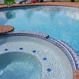 Image of pool overlooking built in spa with blue tiles with wave pattern and blue glass tiles inset into the seat of the spa.